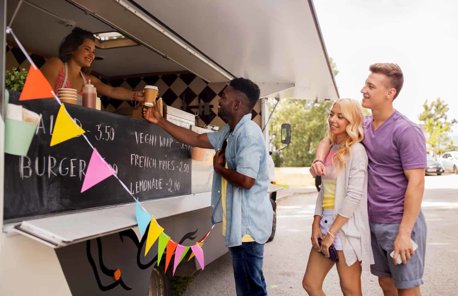 A group of people standing in front of a food truck.