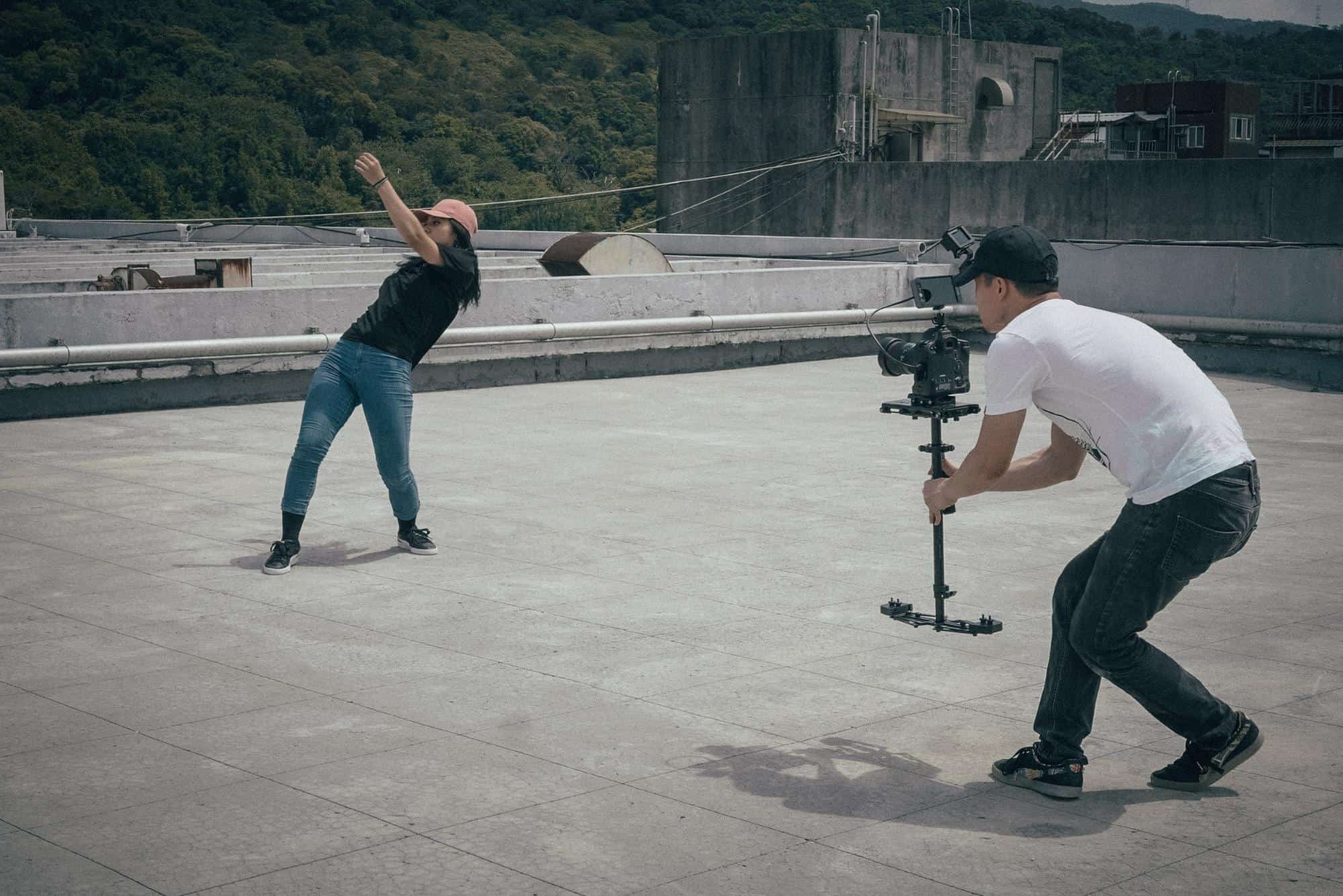 A camera man taking a video of a girl in a roof top.