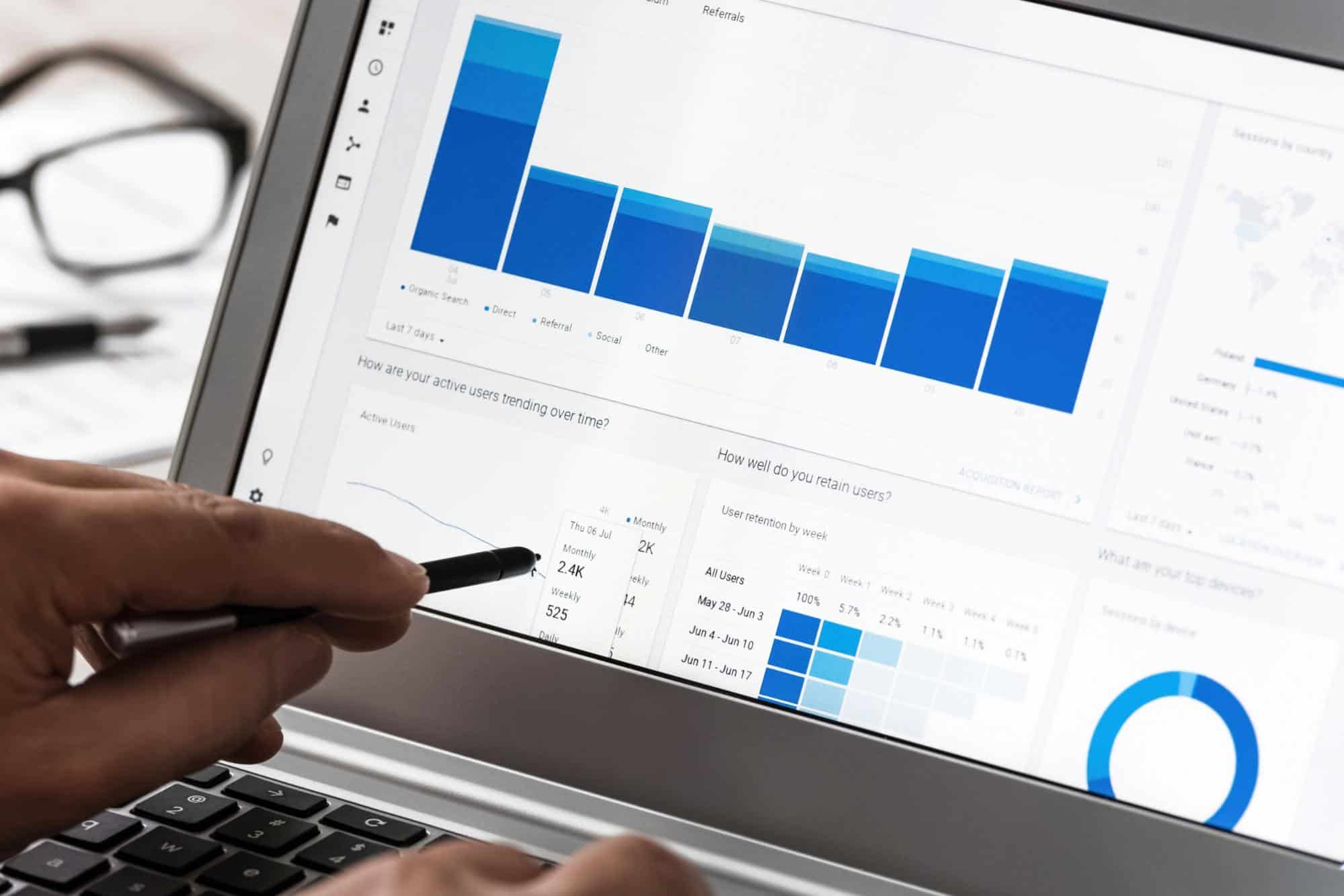 A person using a laptop with a graph on the screen.