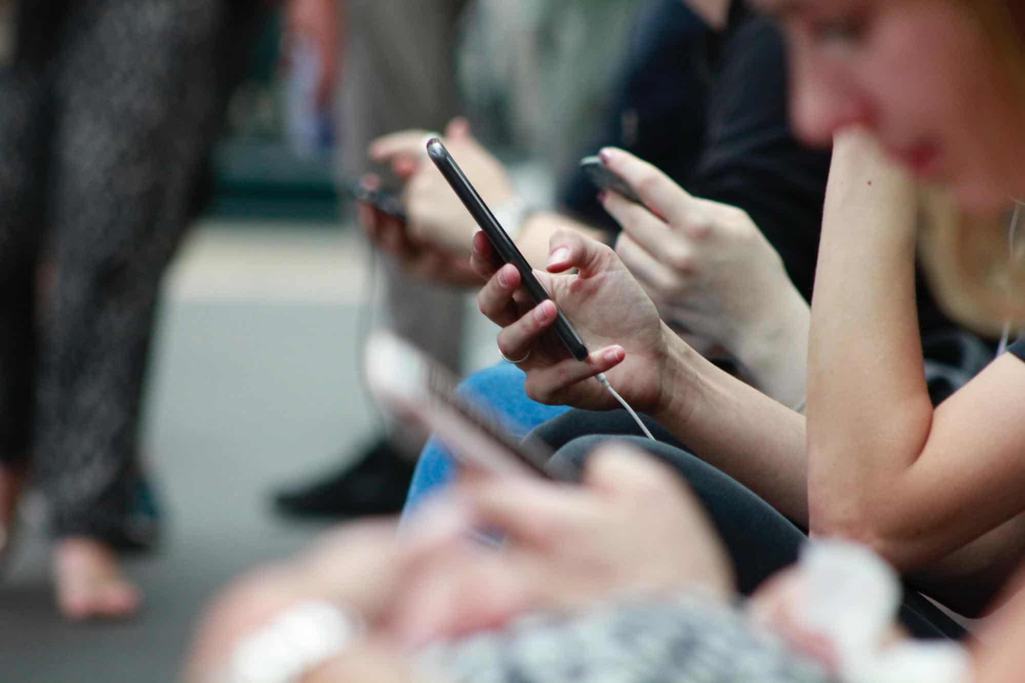 image2 group of people sitting on a sidewalk holding their cell phones.