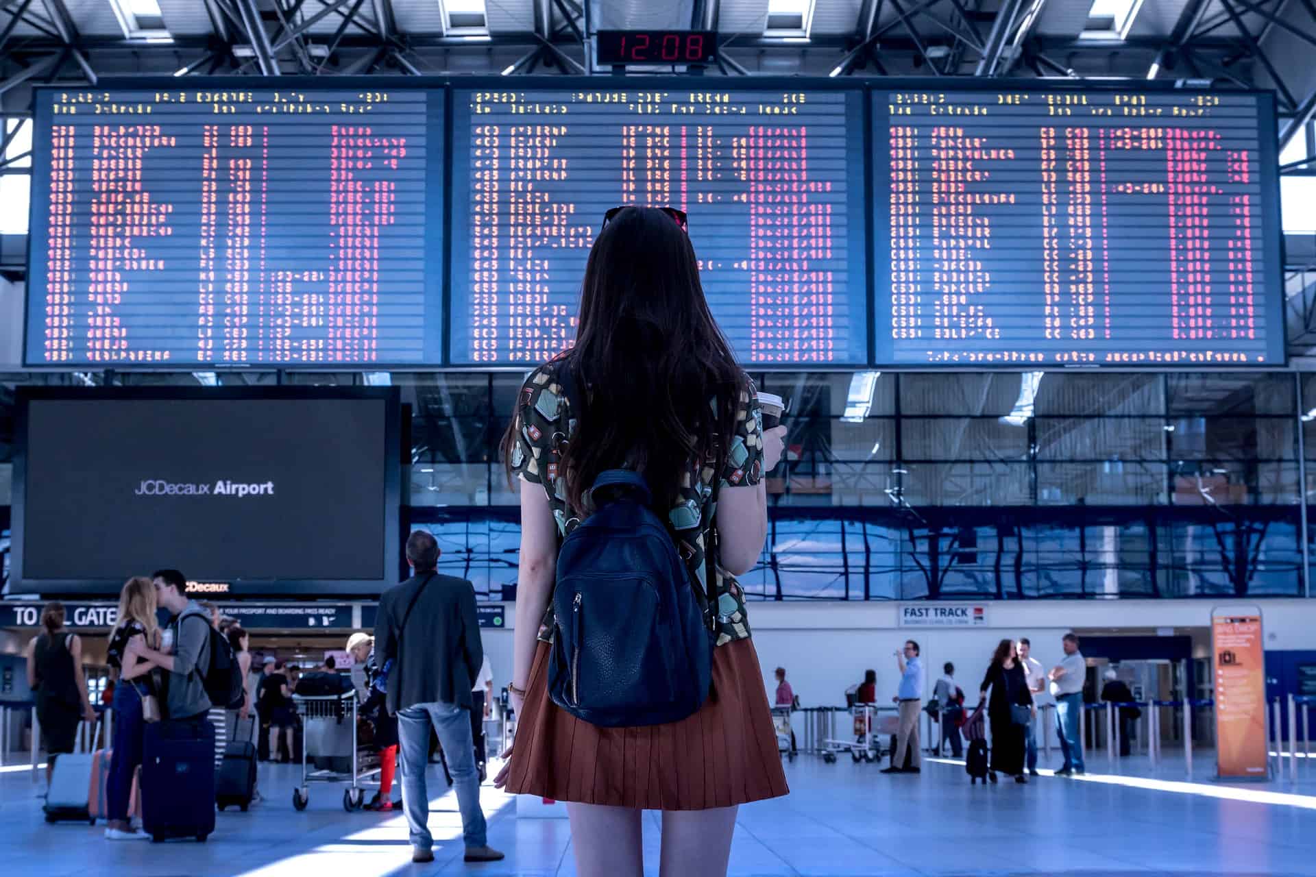 Woman standing in front of a time board at the airport.