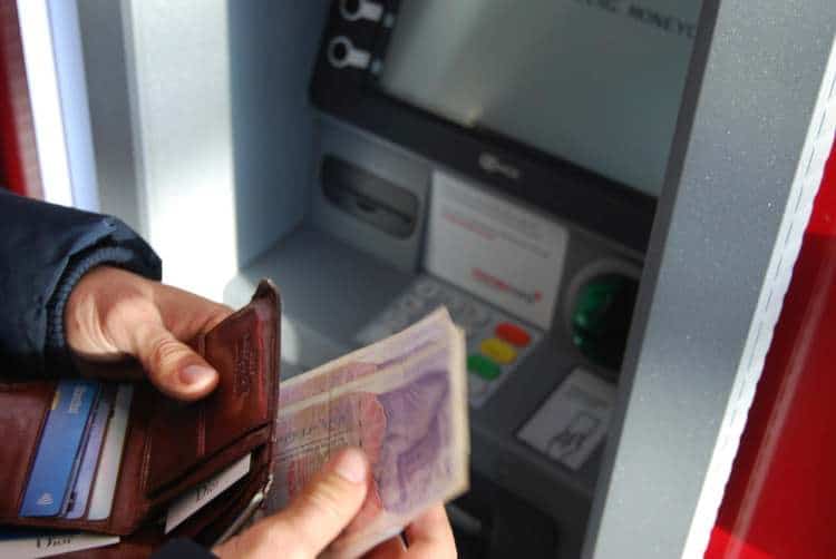 A person is withdrawing's money into an atm machine.