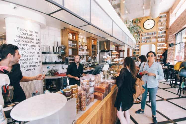 A group of people standing at a counter in a coffee shop.