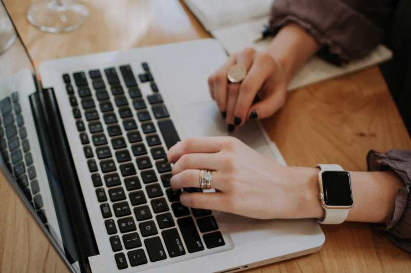 A woman typing on a laptop with an apple watch.
