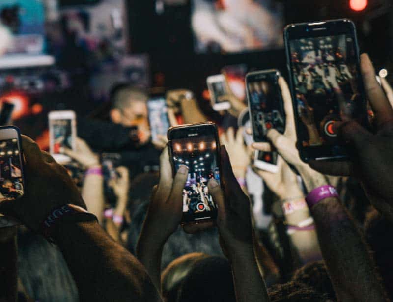 A crowd of people holding up their phones at a concert.