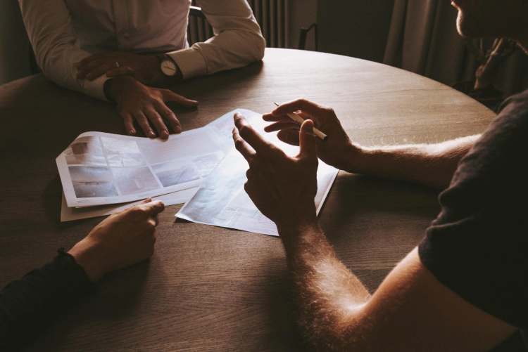 A group of people sitting around a table with papers.