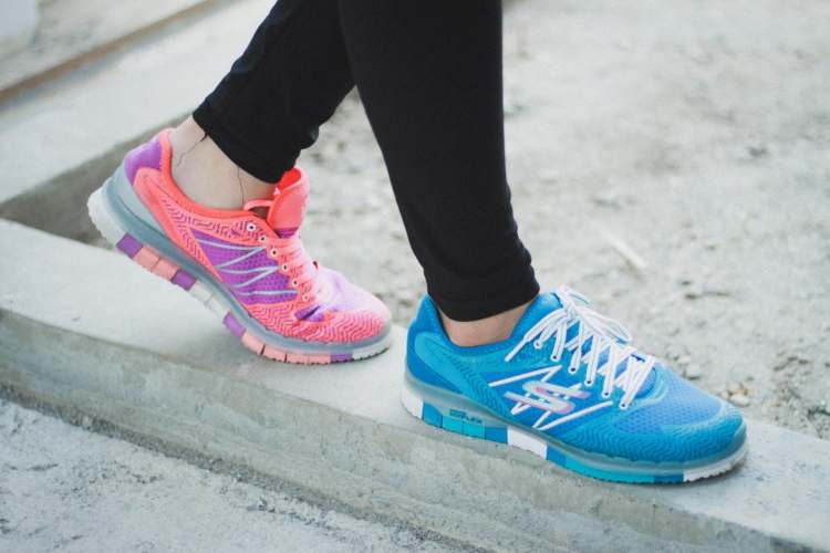 A woman wearing a pair of blue and pink sneakers.