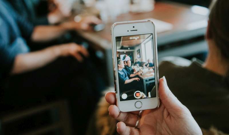 A person holding up a cell phone to take a picture of a group of people.