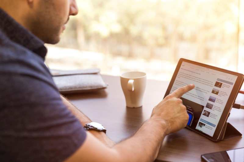 A man is using an ipad at a desk.