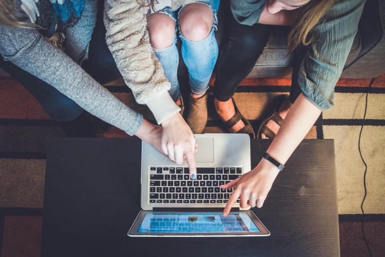 A group of friends looking at a laptop.