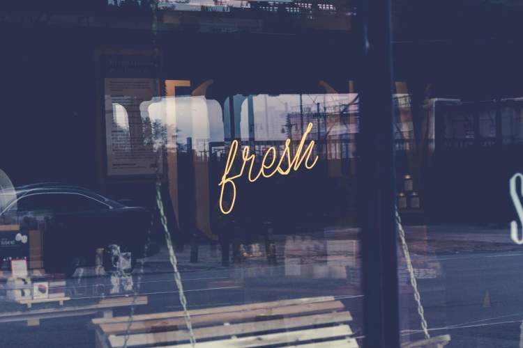 A sign that says fresh in the window of a store.