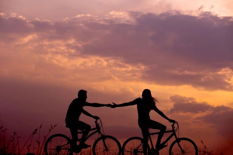 Silhouettes of a couple riding bicycles at sunset.