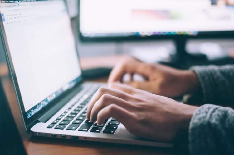 A person typing on a laptop at a desk.