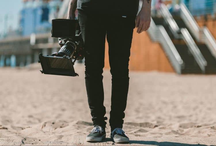 A man holding a camera on the beach.