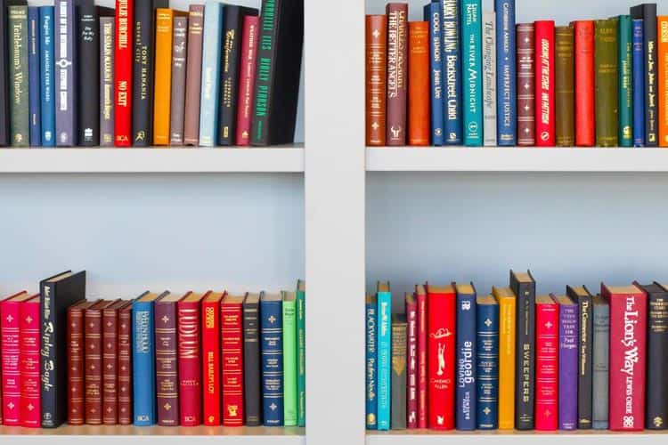 A shelf of colorful books on a white shelf.