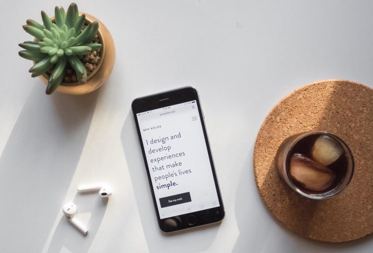 mobile-friendly-website A smartphone on a table next to a cup of coffee and a cactus.