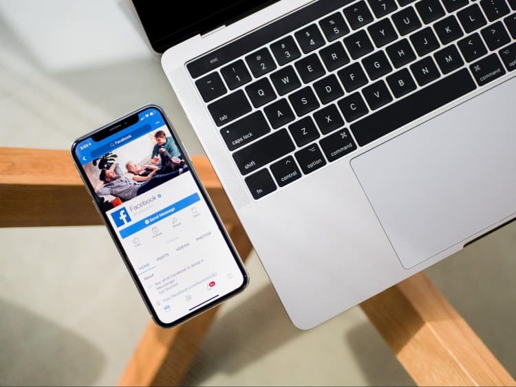 A laptop with a phone on it next to a wooden table.