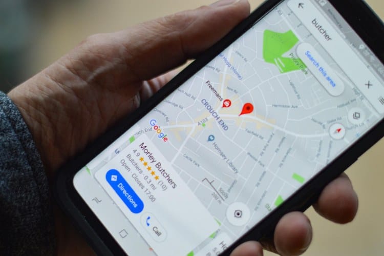 A person holding a cell phone with a google map on it.