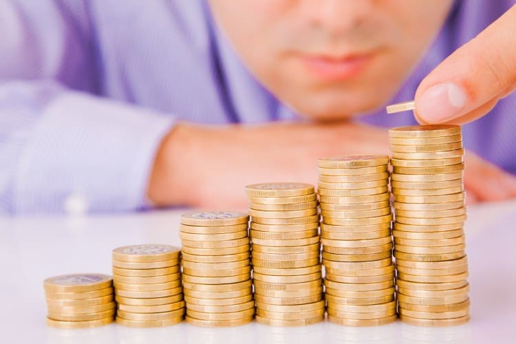 A man is putting coins on top of a stack of coins.