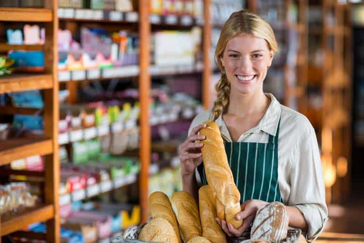 A woman in an apron holding a basket of bread.