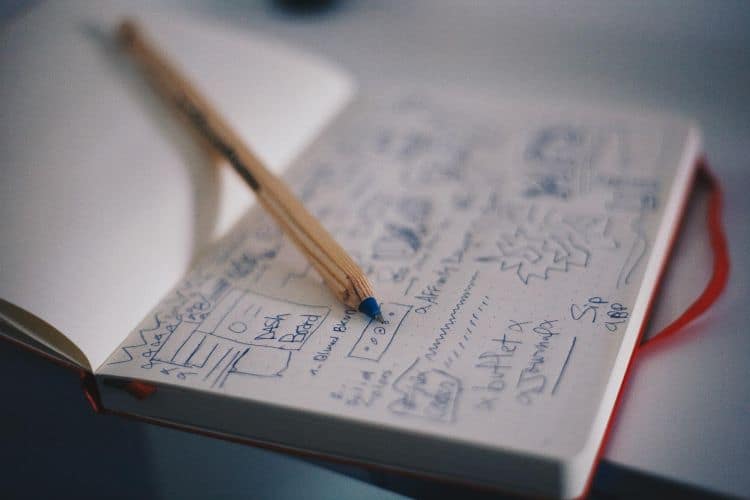 A notebook with a pencil sitting on top of it.