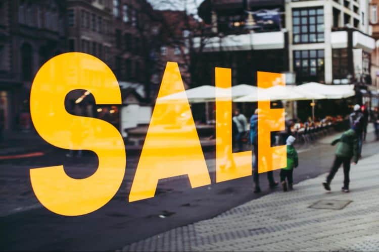 A sale sign on a window in a city.