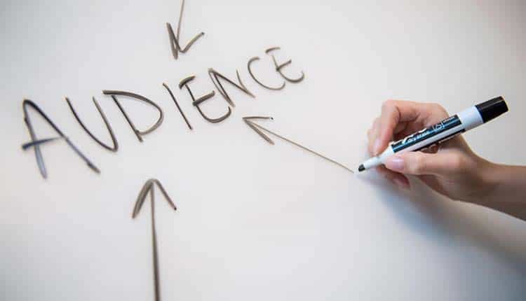 A person writing the word audience on a whiteboard.