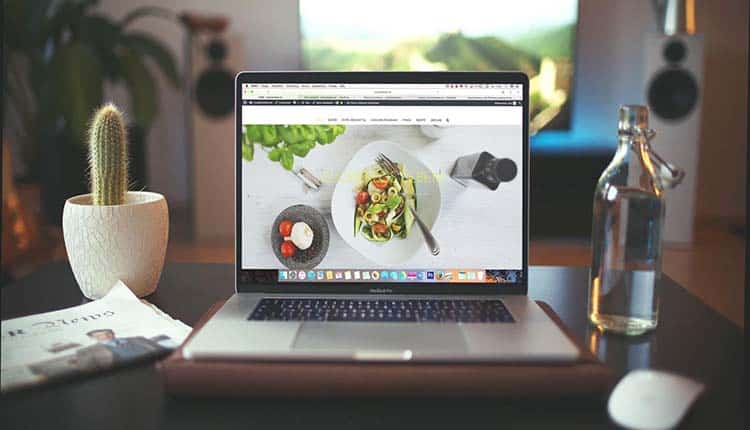 A laptop with a food website on it sitting on a table.