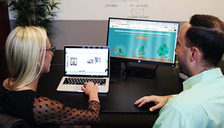 Negotiation A man and woman sitting at a desk looking at a computer screen.