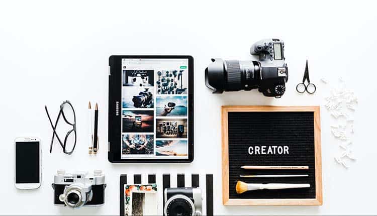 Photography A tablet, camera, and other items on a white table.