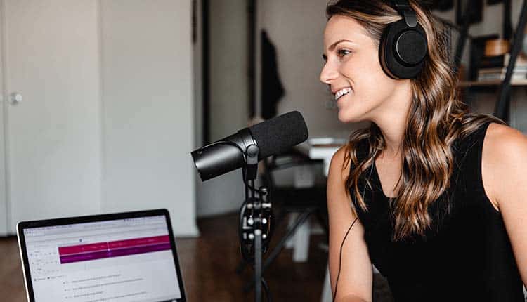 Recording A woman wearing headphones and sitting in front of a laptop.