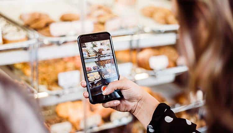 A woman is taking a picture of a display of pastries.
