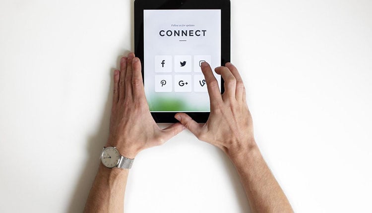 A hand holding an iPad that shows the word Connect