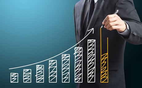 A businessman drawing a bar graph on a blue background.