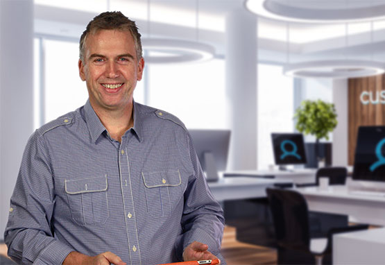 A man standing in an office holding an orange folder.