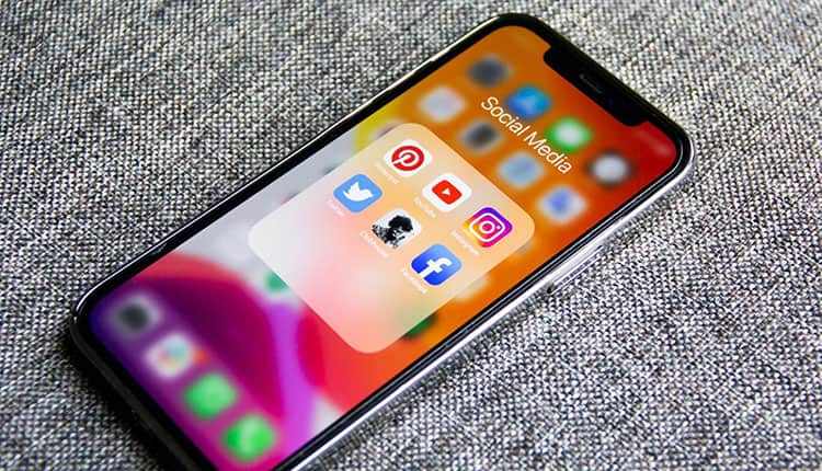 A phone with social media icons displayed on it.