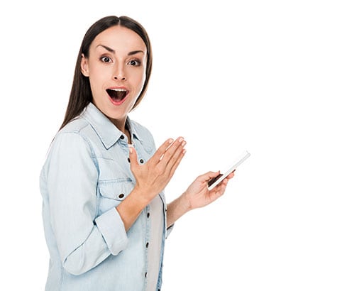 A woman holding a cell phone and looking surprised.