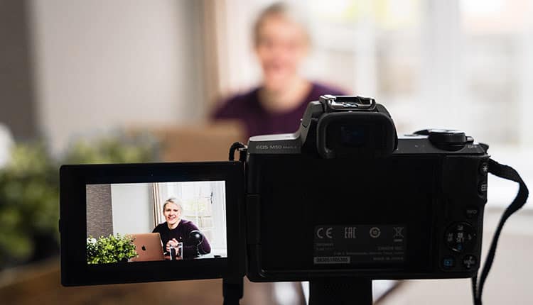 Digital camera focused on a woman on laptop screen, with camera's display clearly showing the video recording setup.