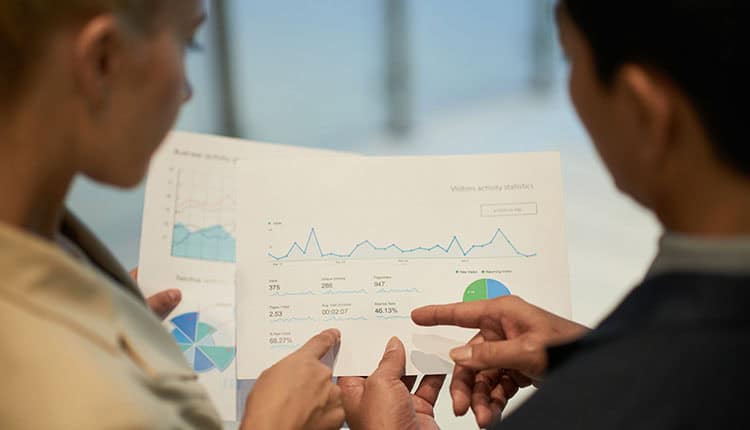 Financial managers analyzing data in report with charts and diagrams